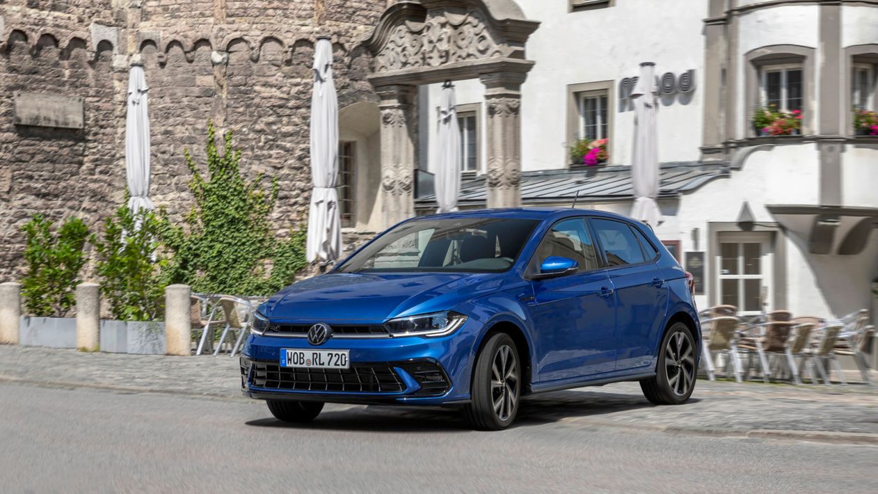 Polo fährt gerade auf die Straße, dahinter befindet sich ein Café.