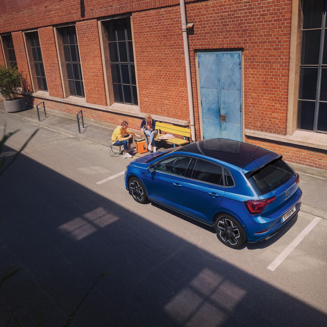 Pärchen spielt Schach und sitzt seitlich vor einem blauen VW Polo R-Line