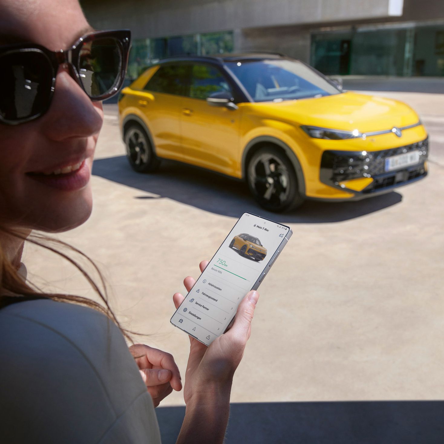 Eine Frau nutzt die App VW Connect nahe ihres VW T-Roc R-Line.