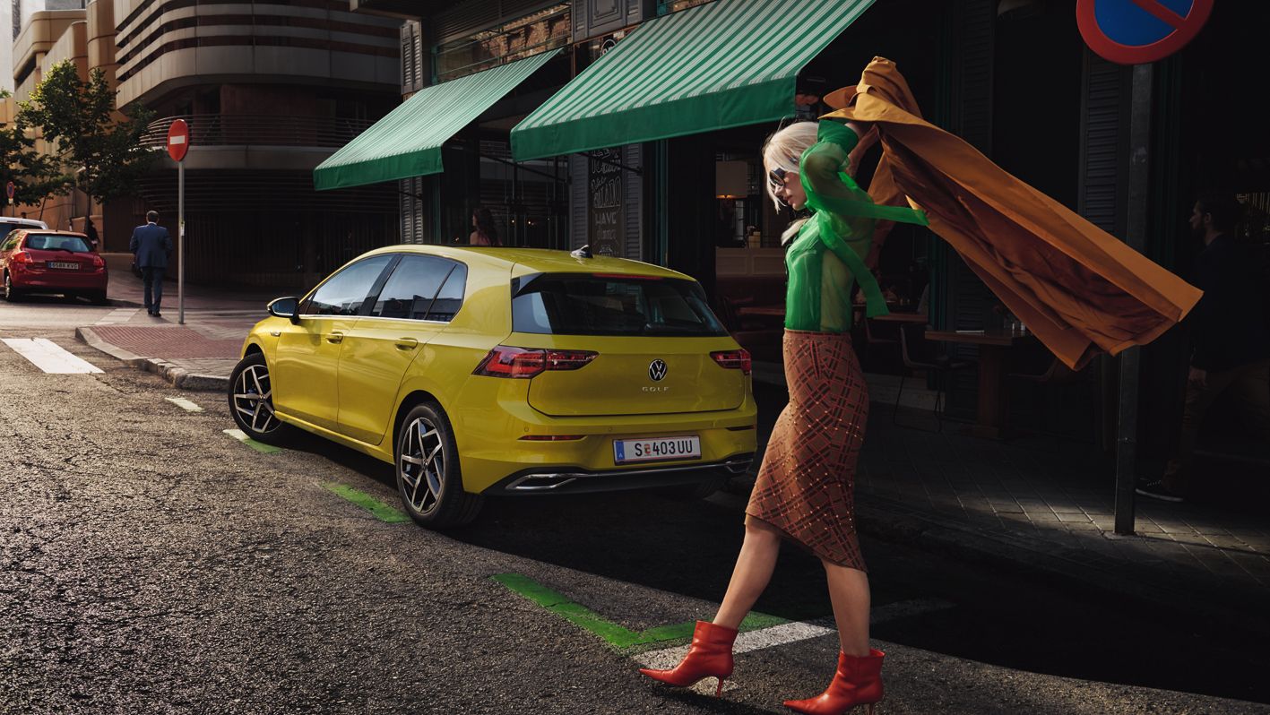 VW Golf Pamja e pasme, gruaja vesh pallton përpara saj.