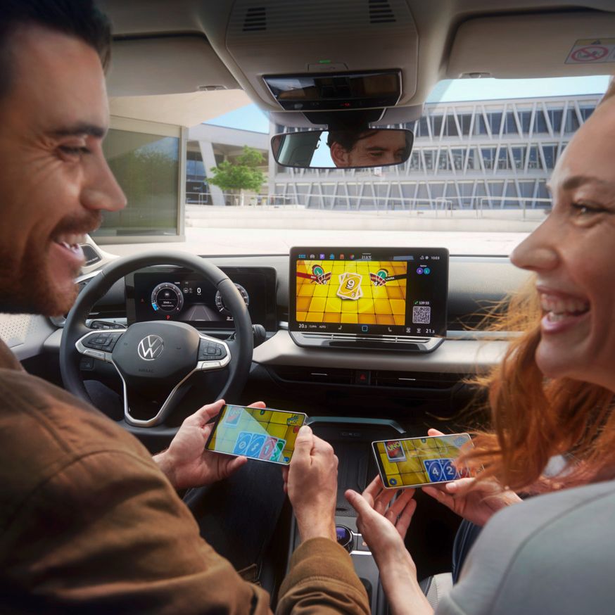 Ein Paar im VW T-Roc Style spielt Uno via AirConsole mit Smartphones als Controller..