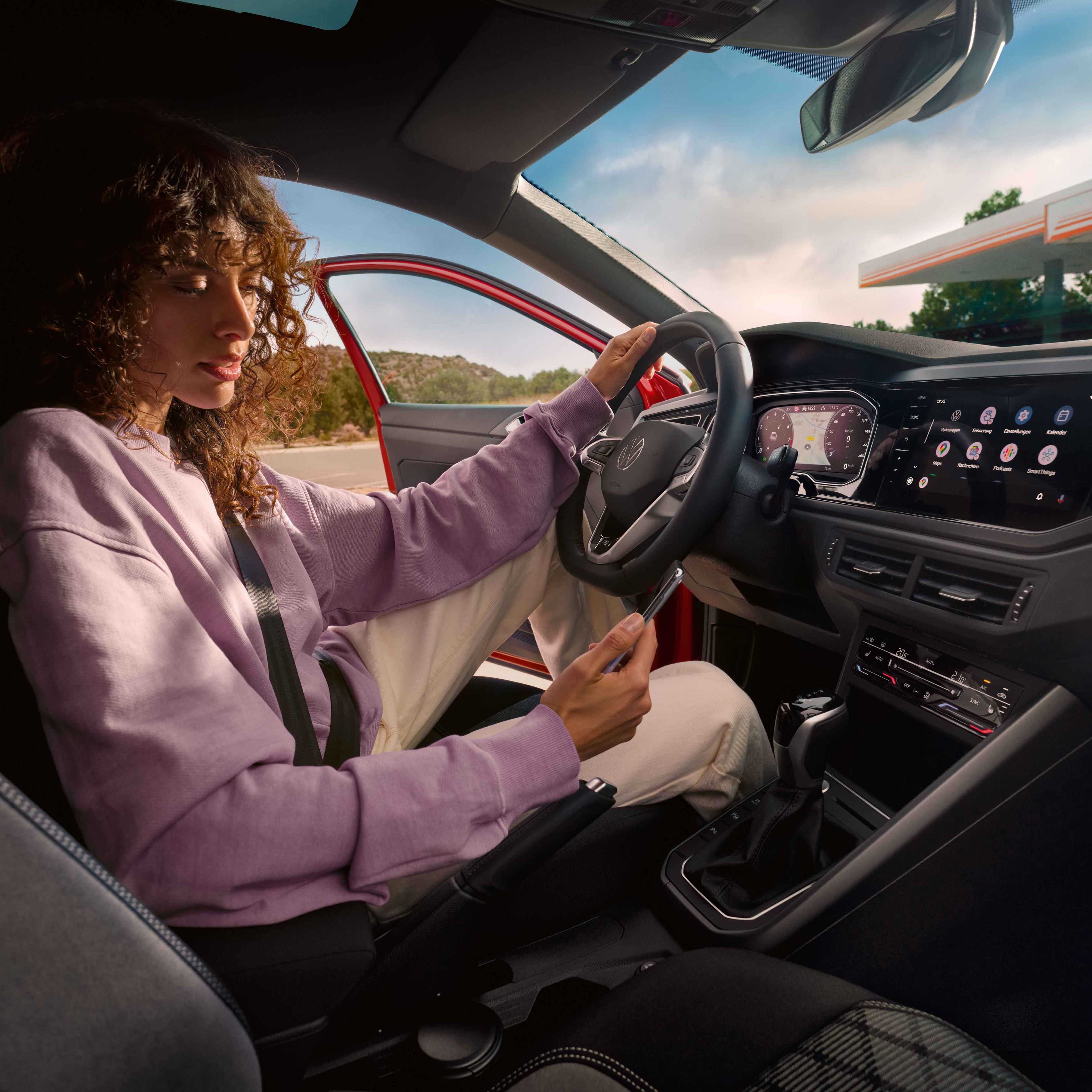 Frau sitzt in VW Taigo R-Line und blickt auf ihr Smartphone