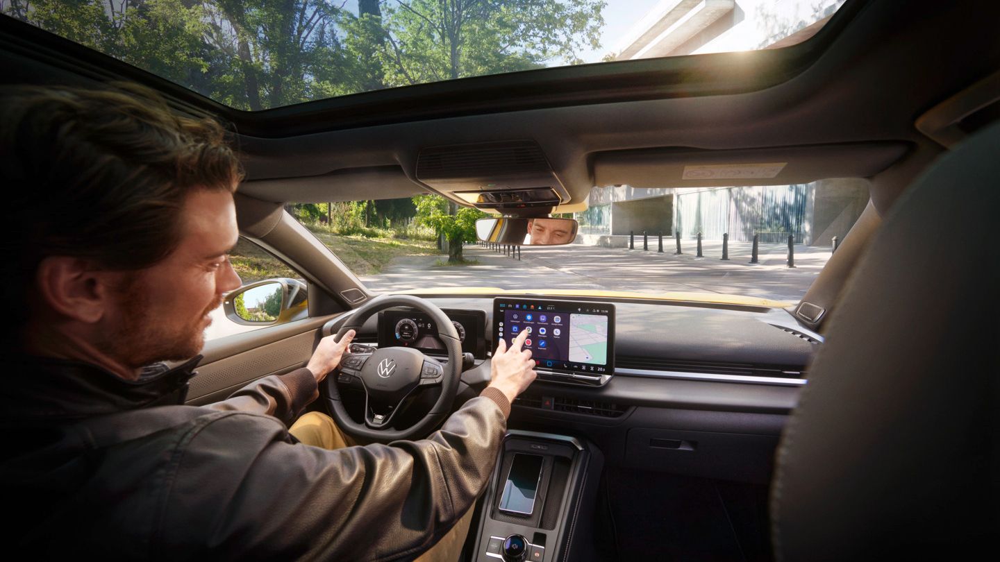 Ein Mann bedient auf dem Infotainment-Display in seinem Volkswagen T-Roc Android Auto über die App-Connect Schnittstelle.