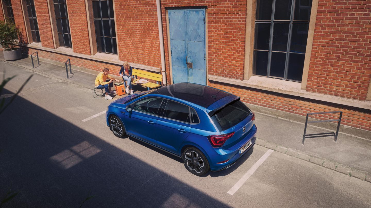 Pärchen spielt Schach und sitzt seitlich vor einem blauen VW Polo R-Line