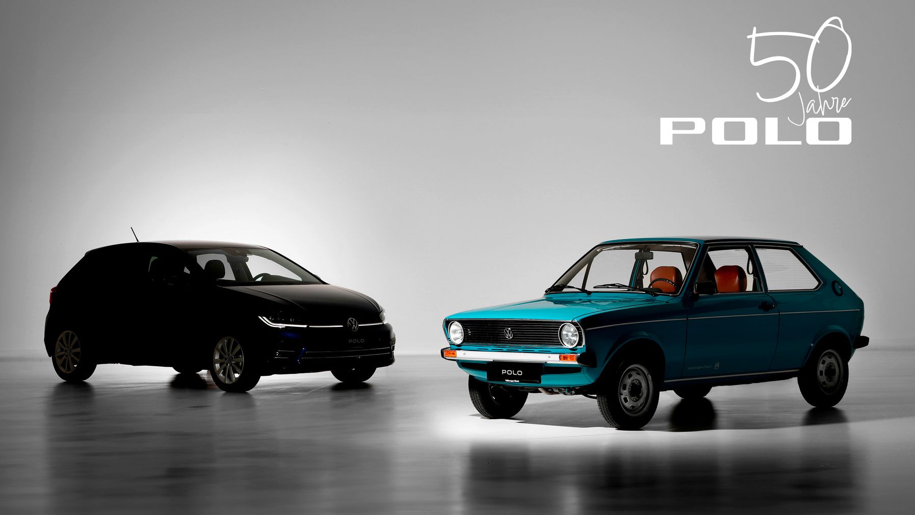 Zwei Volkswagen Polo Modelle nebeneinander: ein moderner schwarzer Polo und ein klassischer blauer Polo aus den frühen Jahren. Im Hintergrund steht „50 Jahre Polo“ geschrieben. Beleuchtung betont die Unterschiede zwischen den beiden Fahrzeugen.