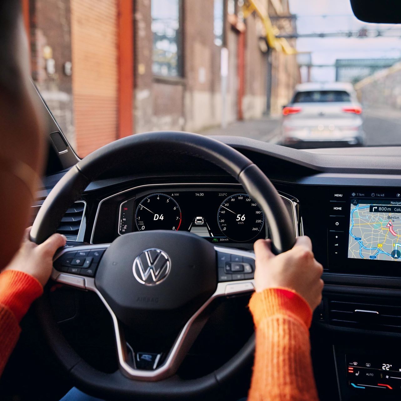 Eine Frau fährt einen VW Polo mit aktiver Navigation auf dem Display des Infotainment-Systems.