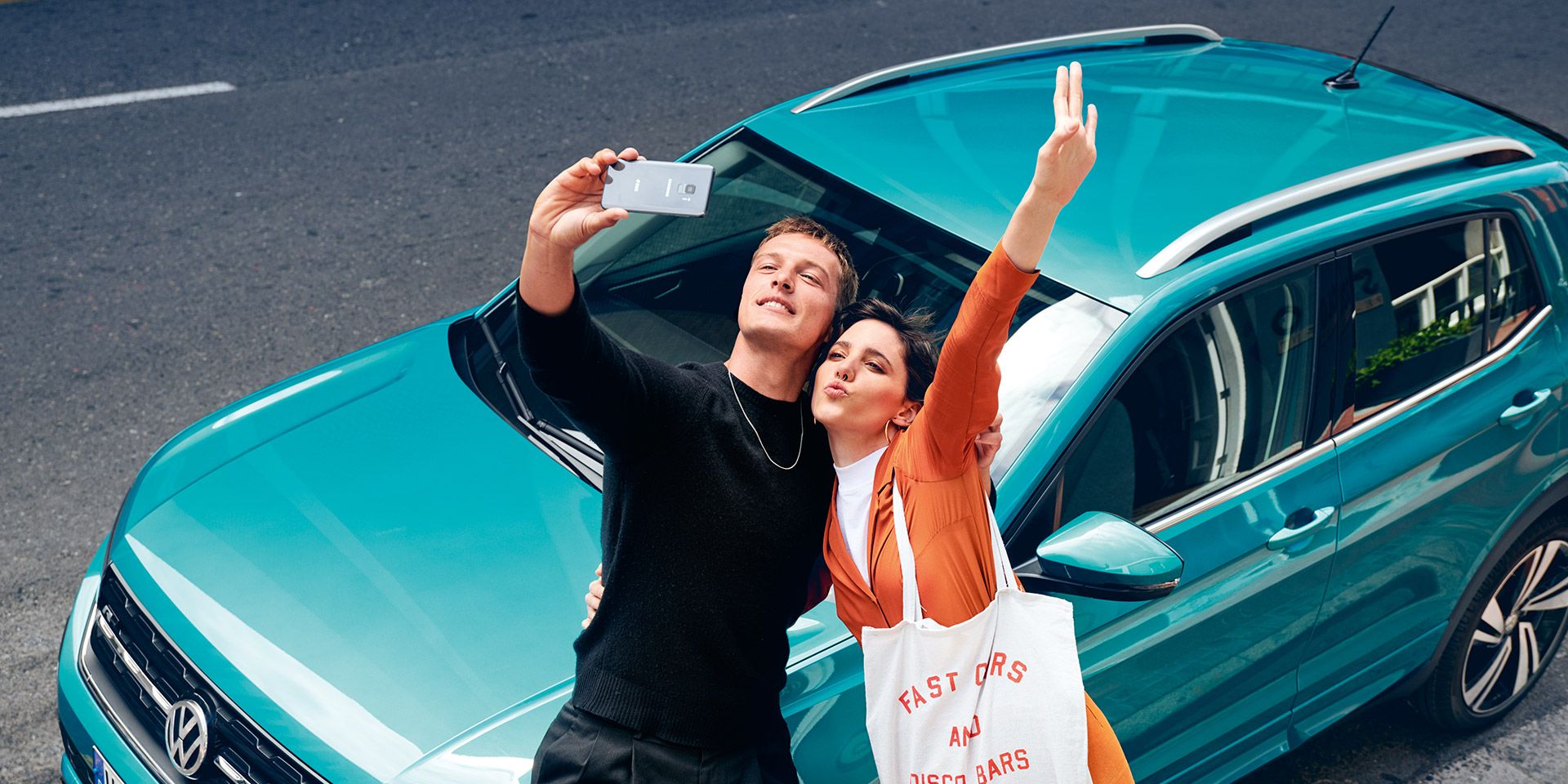 Ein Pärchen steht vor dem VW T-Cross und macht ein Selfie