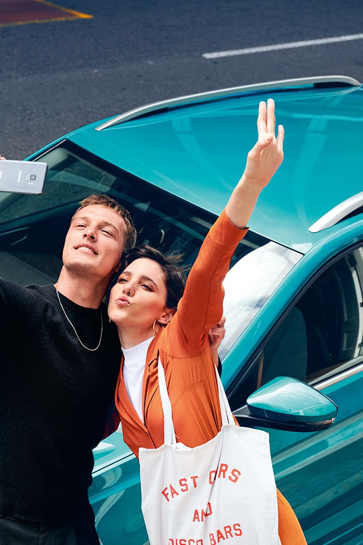 Ein Pärchen steht vor dem VW T-Cross und macht ein Selfie