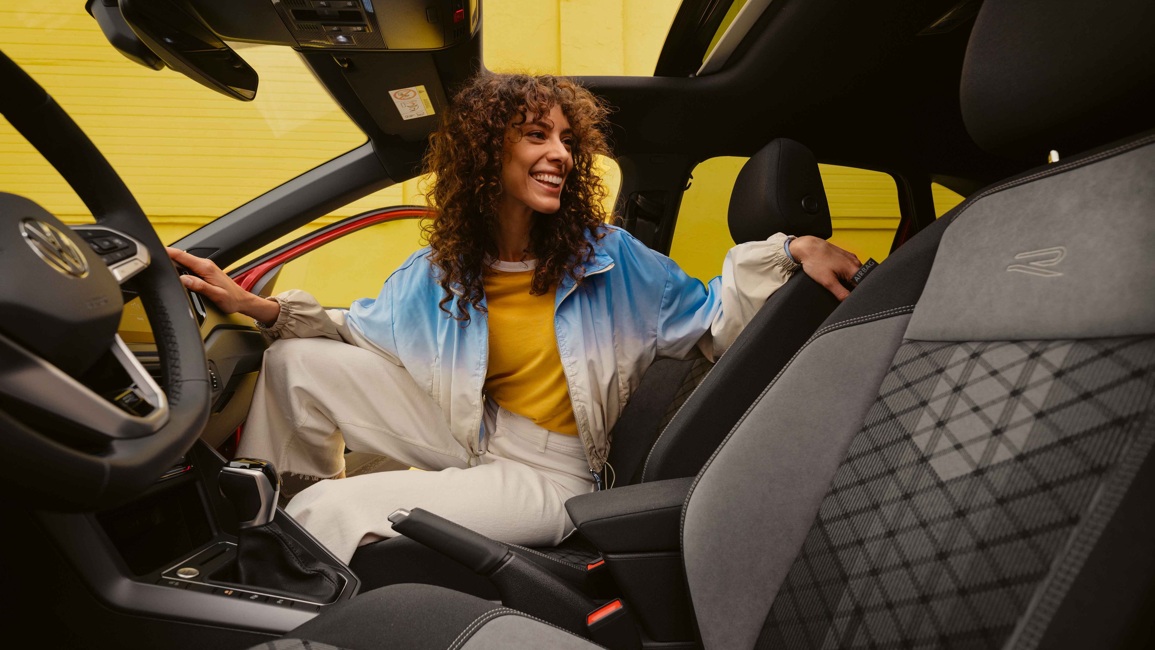 Frau sitzt am Beifahrersitz eines VW Taigo R-Line und blickt zur Rückbank