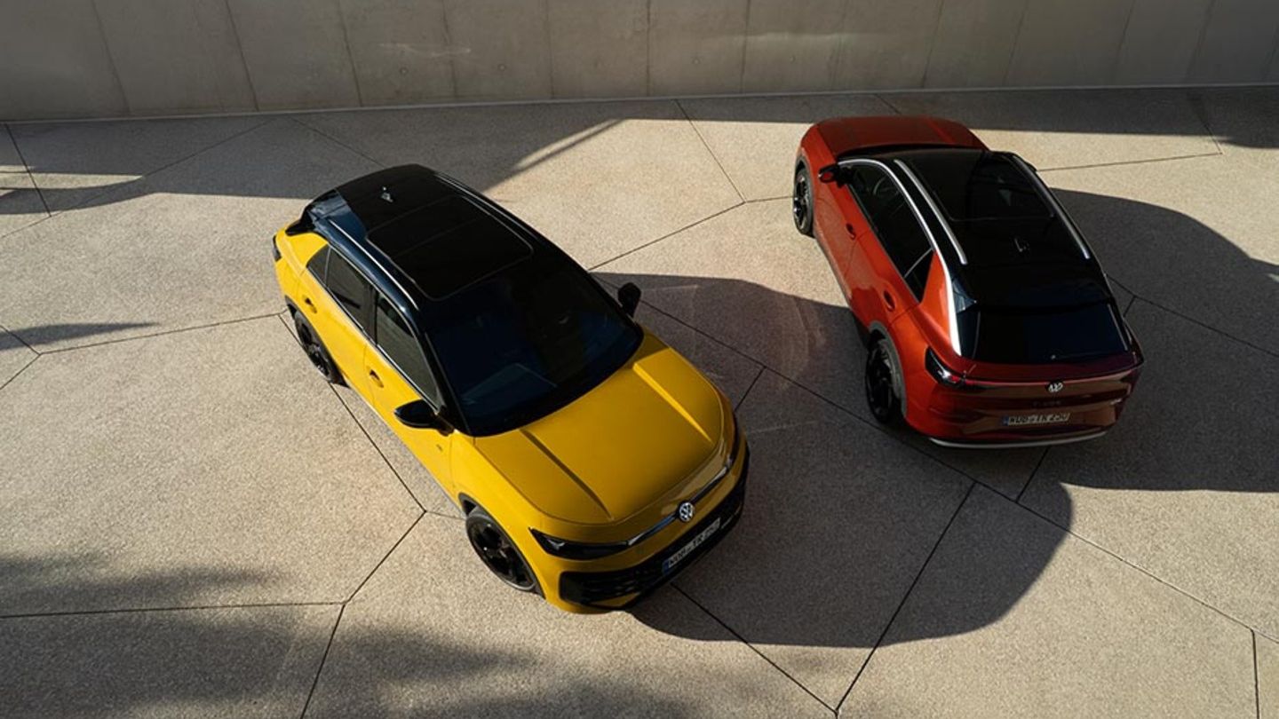 Ein gelber VW T-Roc R-Line und ein roter VW T-Roc Style von schräg oben vor einem modernen Gebäude.