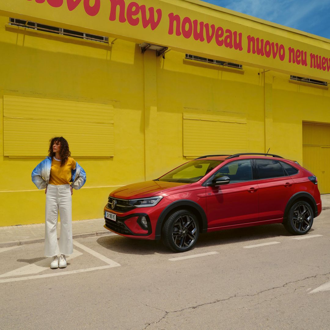 Geparkter Taigo R-Line Black Style neben gelbem Haus mit Person daneben